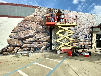 Ted Hanson and Frank Wilson on a scissor lift working on the upper levels of the Oroville Gold Mine Mural.  